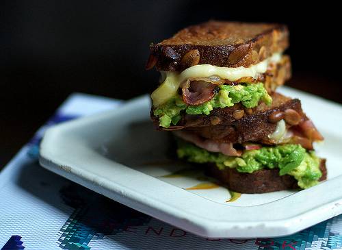 Grilled sandwich with avocado, cheese, bacon and an apple